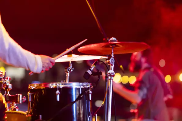 Drumset Nahaufnahme, Blick über Schulter von Schlagzeuger auf der Bühne, rotes Festivallicht